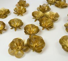 many golden flowers are arranged on a white surface with one flower in the middle and several petals out