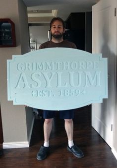 a man standing in front of a sign that says gummy hoff asylum