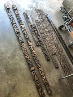 five wooden carvings sitting on top of a floor next to a pile of metal bars