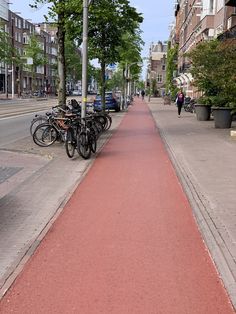 there are many bikes parked on the side of this street and people walking down the sidewalk