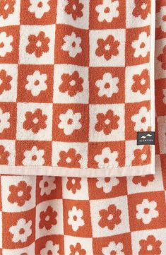 an orange and white checkered blanket with flowers on the front, in full view