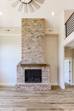 an empty living room with a brick fireplace