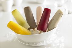 there are five different colored pops in a bowl with sugar on the table next to it