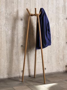 a coat rack with two coats hanging from it's sides and a blue towel on top