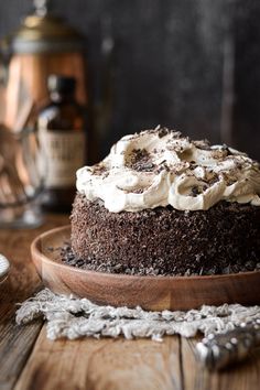 a chocolate cake on a wooden plate with whipped cream frosting and cinnamon in the background