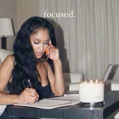 a woman sitting at a table with a notebook and pen in her hand