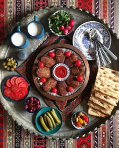 a platter filled with meatballs, olives, tomatoes and other food items