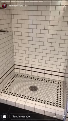 a white tiled shower stall with black and white floor tiles on the walls, and a drain in the middle