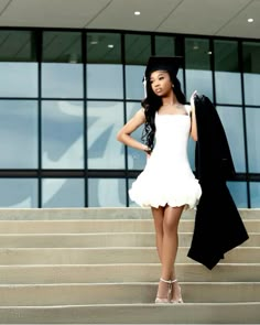 a woman in a white dress and black jacket standing on steps with her hand on her hip