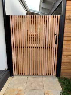 an open wooden gate on the side of a house