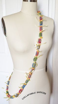 a white mannequin wearing a multicolored beaded necklace on it's neck