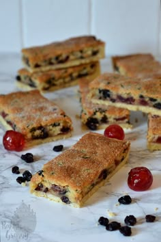 several pieces of cake sitting on top of a counter next to cherries and jelly