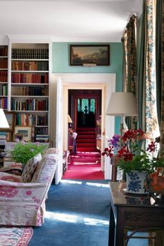 a living room filled with furniture and bookshelves next to a red carpeted floor