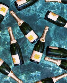 several bottles of champagne sitting in the water together on top of a blue tablecloth