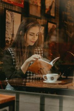 a woman sitting at a table reading a book