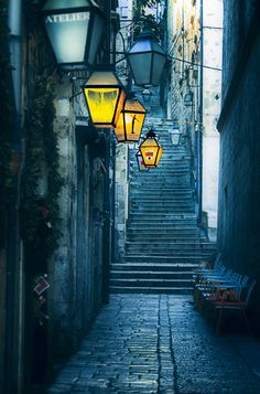 an alleyway with stairs and lanterns hanging from the ceiling