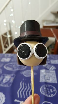 a hand holding a stick with an eyeball and hat on it that is shaped like a man's head