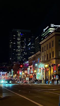 a city street at night with traffic lights and tall buildings in the background, all lit up