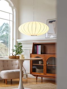 a living room filled with furniture and a white lamp hanging over it's head