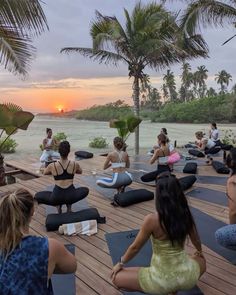 a group of people sitting on yoga mats in front of the ocean with palm trees