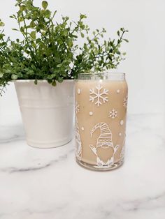 two vases with plants in them sitting on a marble counter top next to each other