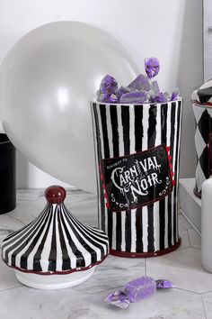 a black and white striped bucket with candy in it next to a balloon on the floor