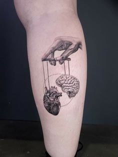 someone is holding their hand over the heart and brain in this tattoo on her leg