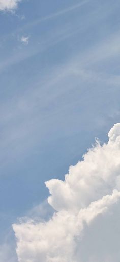 an airplane flying high in the sky with white clouds behind it and blue skies above