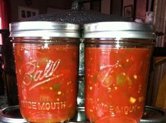 two jars filled with red liquid sitting on top of a stove next to each other