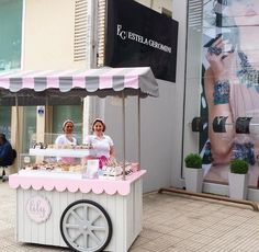 two women standing behind a cart selling food