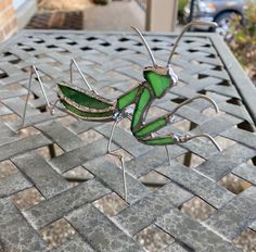 a green insect sitting on top of a metal table