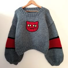 a gray sweater with a red cat on the front and black stripes down the side