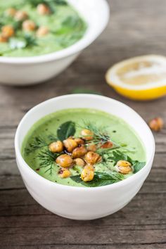 a white bowl filled with green soup and garnished with nuts