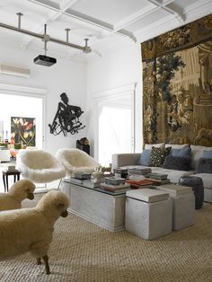 two sheep standing in the middle of a living room with large tapestry on the wall