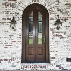 a brick building with double doors and two lights on the side walk next to it