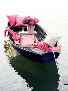 a small boat with pink pillows and flowers in it