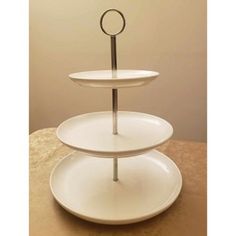 three tiered cake stand with two plates on each side and one plate holding an object in the middle