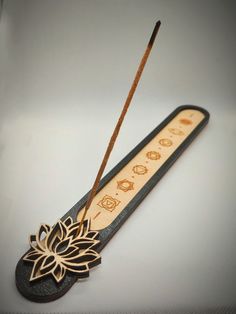 a wooden incense stick with an intricate flower design on it's side and two sticks sticking out of the back