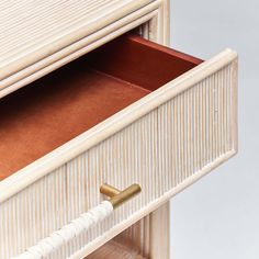 a close up of a drawer with a white handle and gold hardware on the bottom