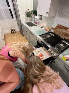 two girls are making cookies in the kitchen