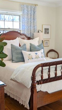 a bed sitting in a bedroom next to a window with blue and white pillows on it