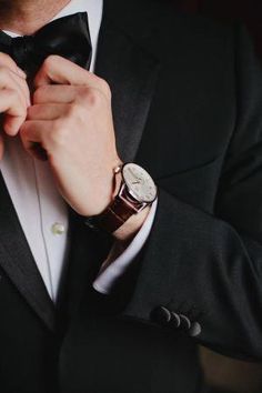 a man in a tuxedo adjusts his watch