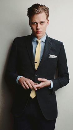 a man in a suit and tie is posing for a photo with his hands on his chest