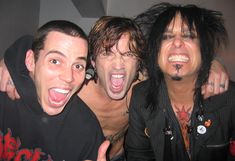 three men posing for the camera with their arms around each other and one man has his tongue out