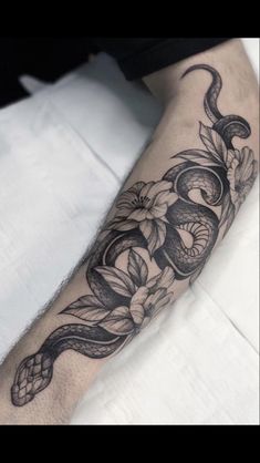 a man's arm with a snake and flowers tattoo on the left side of his arm