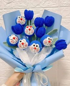 a person holding a bouquet of blue flowers with cat faces on the top and bottom