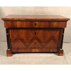 an antique chest of drawers with brass hardware and wood inlays, on display