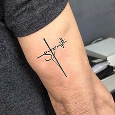 a person with a tattoo on their arm that reads strength and has a cross in the middle