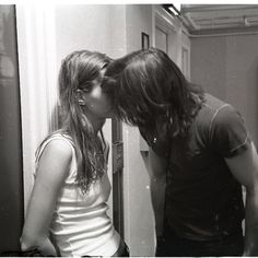 a man and woman kissing in front of a mirror