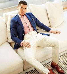 a man sitting on top of a white couch wearing a blue jacket and pink shirt